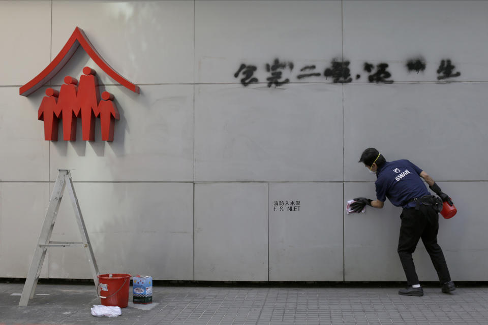 A worker cleans up a vandalized wall Monday, Dec. 9, 2019, in Hong Kong. Hundreds of thousands of demonstrators crammed into Hong Kong's streets on Sunday, their chants echoing off high-rises, in a mass show of support for the protest movement entering its seventh month. (AP Photo/Kiichiro Sato)