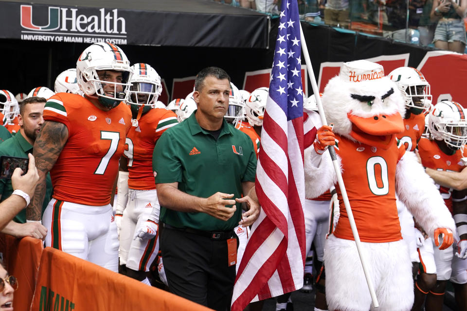 Miami head coach Mario Cristobal, center, prepares to run onto the field before an NCAA college football game against Bethune Cookman, Saturday, Sept. 3, 2022, in Miami Gardens, Fla. (AP Photo/Lynne Sladky)
