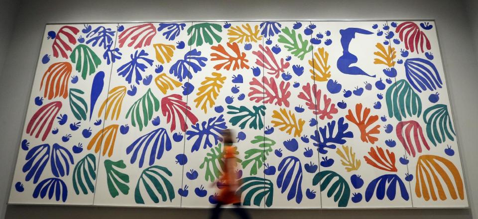 A woman a walks past 'The Parekeet and the Mermaid 1952' by Henri Matisse, on display during a media opportunity at The Tate Modern in London, Monday, April 14, 2014. The artwork is part of the 'Henri Matisse: The Cut-Outs' exhibition that runs at the gallery from April 17 until Sept. 7, 2014. (AP Photo/Kirsty Wigglesworth)