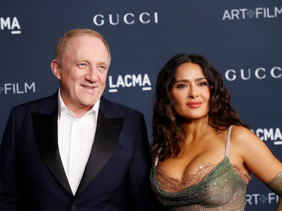 Francois-Henri Pinault and Salma Hayek stand in front of background that reads Gucci