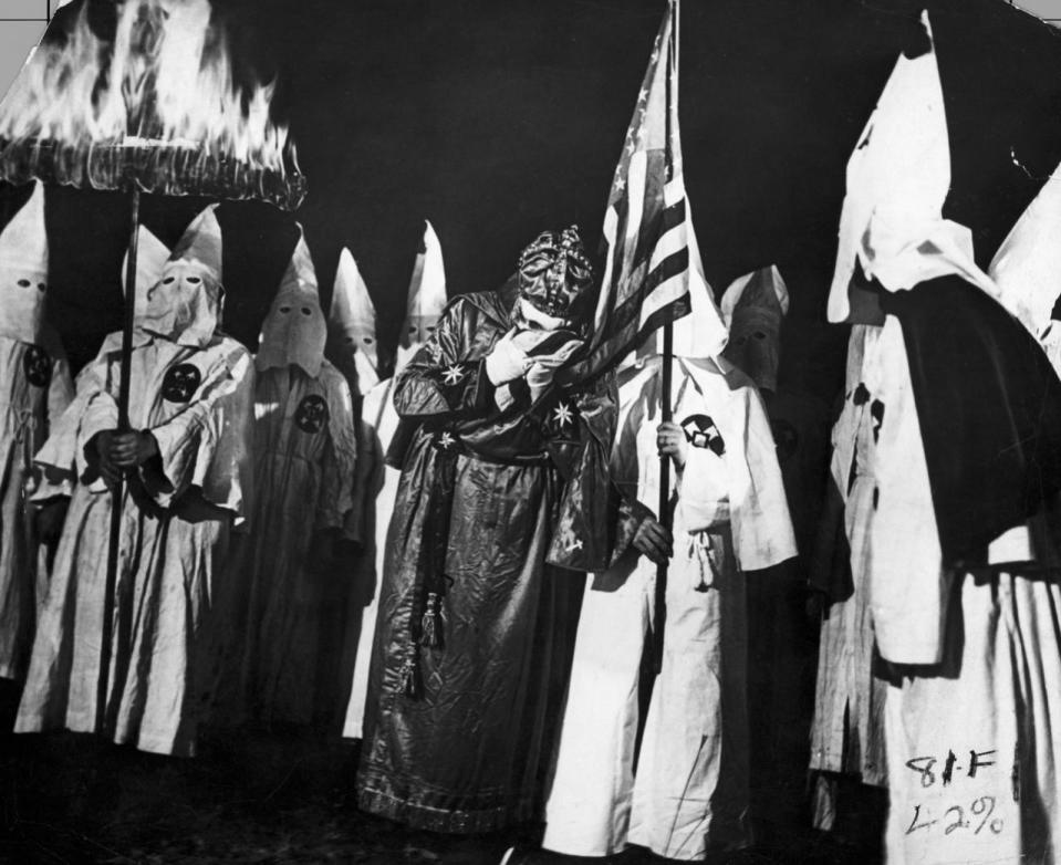 <p>The Imperial Wizard of the Ku Klux Klan sets the example of loyalty to the U.S. Government by kissing the flag, which, with the fiery cross are symbols of the Klan. (Photo: Getty Images </p>