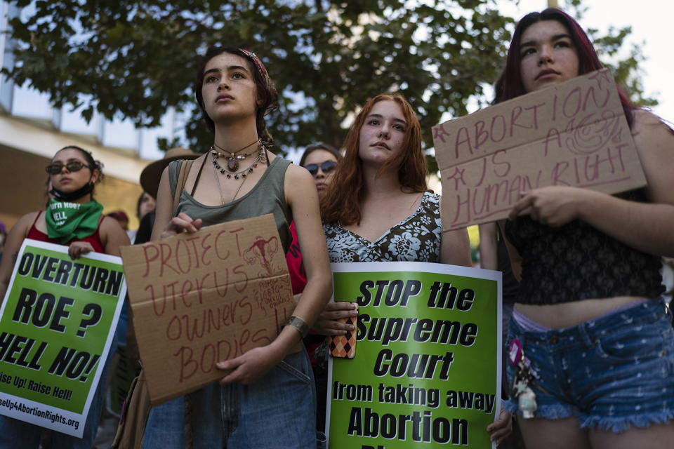 People holding signs, including "Stop the Supreme Court from taking away abortion" and "protect uterus owners' bodies"