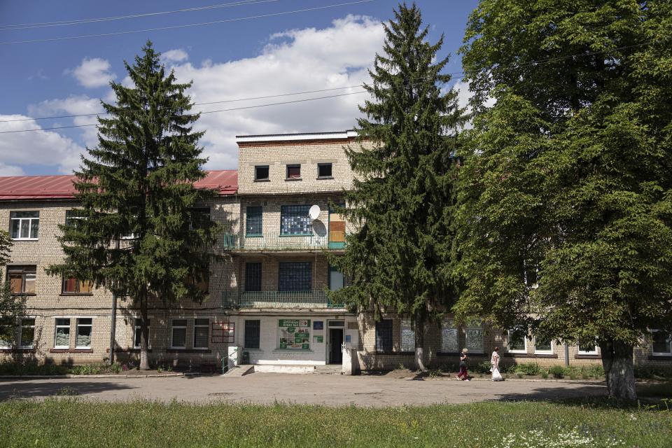 Local residents walk past the hospital in Zolochiv, Kharkiv region, Ukraine, Sunday, July 31, 2022. Ukraine's health care system already was struggling due to corruption, mismanagement and the COVID-19 pandemic. But the war with Russia has only made things worse, with facilities damaged or destroyed, medical staff relocating to safer places and many drugs unavailable or in short supply. (AP Photo/Evgeniy Maloletka)