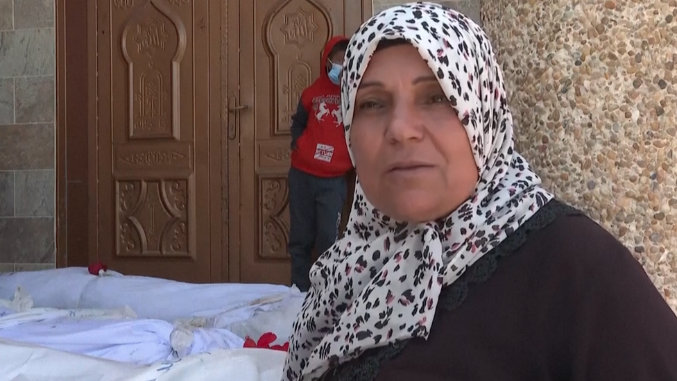 Kareema Elras stands next to bodies exhumed from Nasser hospital, in Khan Younis, southern Gaza (24 April 2024)