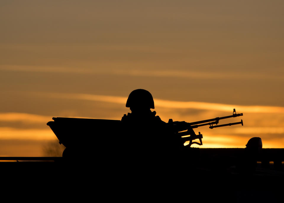 A pro-Russian soldier is silhouetted by the sunset sky as he mans a machine gun outside a Ukrainian military base in Perevalne, Ukraine, Saturday, March 15, 2014. Tensions are high in the Black Sea peninsula of Crimea, where a referendum is to be held Sunday on whether to split off from Ukraine and seek annexation by Russia. (AP Photo/Vadim Ghirda)