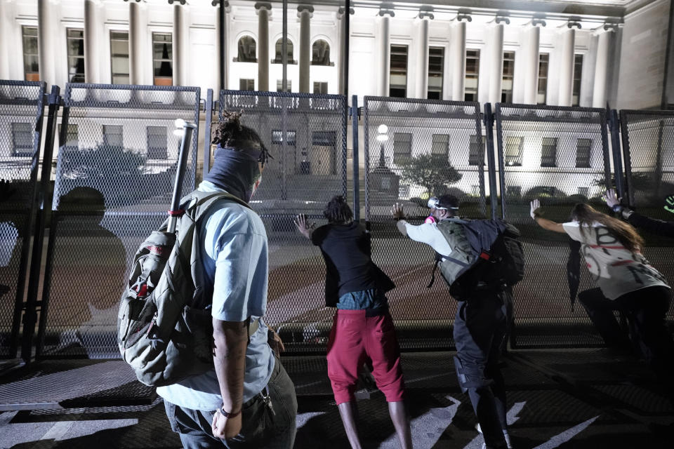 People try to push over protective fencing Tuesday, Aug. 25, 2020 in Kenosha, Wis. Anger over the Sunday shooting of Jacob Blake, a Black man, by police spilled into the streets for a third night. (AP Photo/Morry Gash)