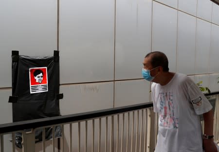 A man looks at a defaced poster of Hong Kong's Chief Executive Carrie Lam in Hong Kong