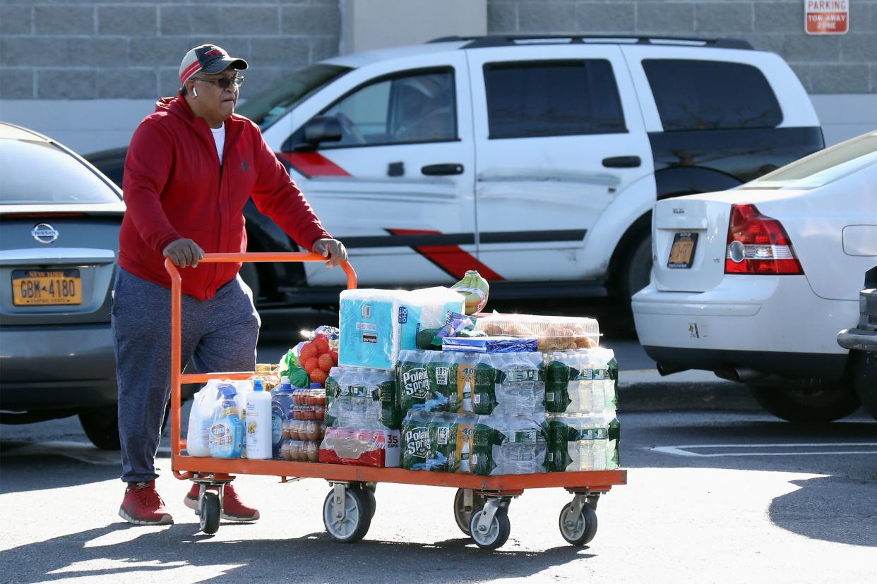 man with large cart full of items from Costco