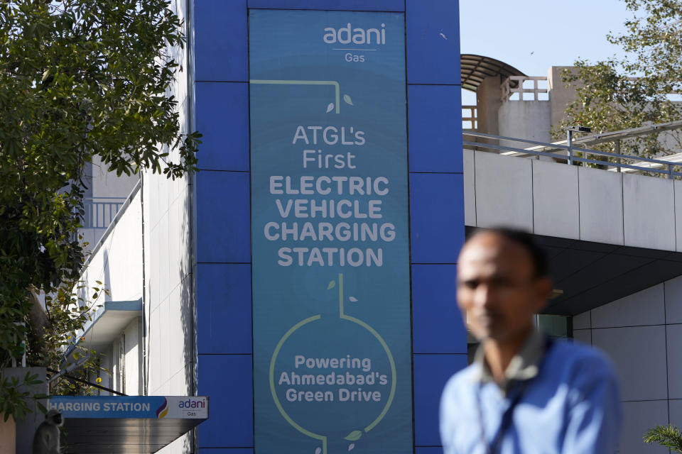 A man walks past an Adani electric vehicle charging station in Ahmedabad, India, Feb. 2, 2023. Shares in Adani Enterprises tumbled 26% Thursday, while stock in six other Adani companies fell 5%-10%. Adani slid from being the world’s third richest man to the 13th as his fortune sank to $72 billion, according to Bloomberg’s Billionaire Index. (AP Photo/Ajit Solanki)