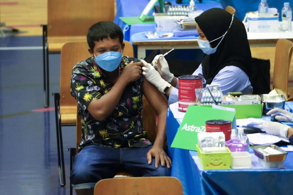 A health worker administers a dose of the AstraZeneca COVID-19 vaccine to a man in Bangkok, Thailand, Wednesday, Feb. 23, 2022. Thailand will ease some entry requirements for foreign visitors as it balances a rising number of coronavirus cases with the need to rebuild its pandemic-damaged economy, the government announced Wednesday. (AP Photo/Sakchai Lalit)