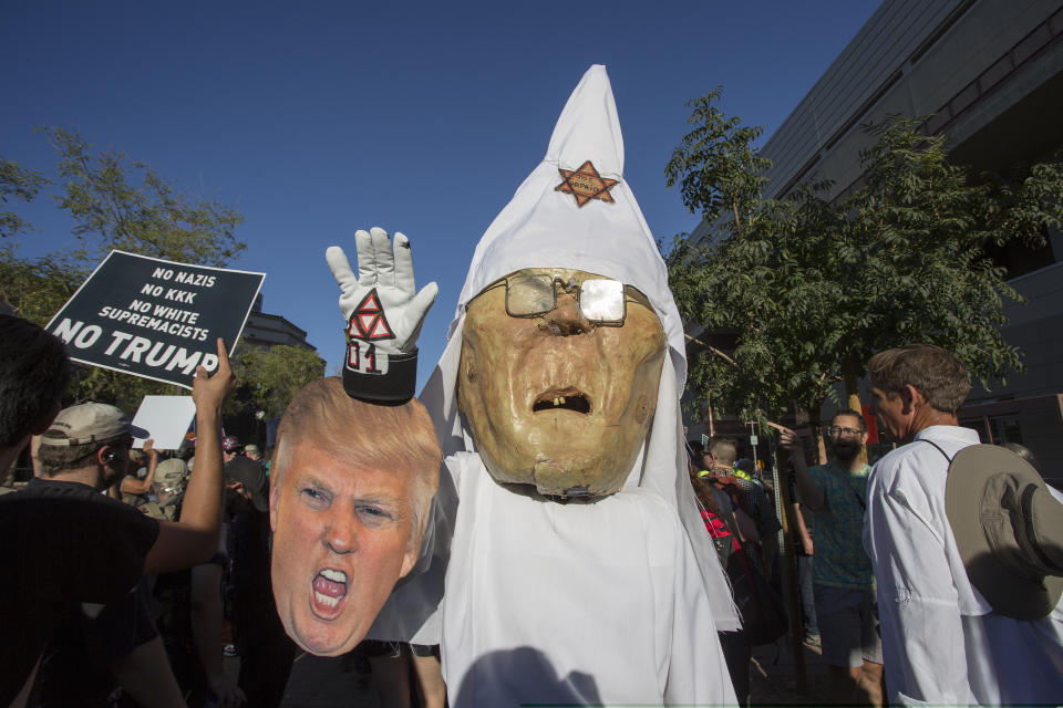 A protester wears a costume likeness of Sheriff Joe Arpaio as a member of the KKK 