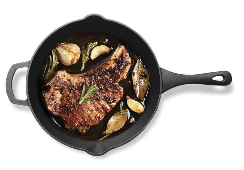 Master Chef Pre-Seasoned Cast Iron Frying Pan with steak and garlic on pan (Photo via Canadian Tire)
