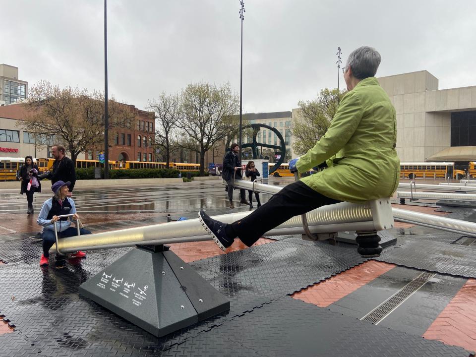 Christine Comito, right, and Deb Madison-Levi play on one of the seesaws that are part of "Impulse" on Thursday, April 18 at Cowles Commons in downtown Des Moines.
