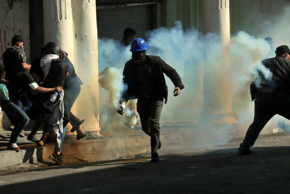 An anti-government protester runs with a tear gas canister fired by police during clashes in Baghdad, Iraq, Nov. 22, 2019. (Photo: Hadi Mizban/AP)