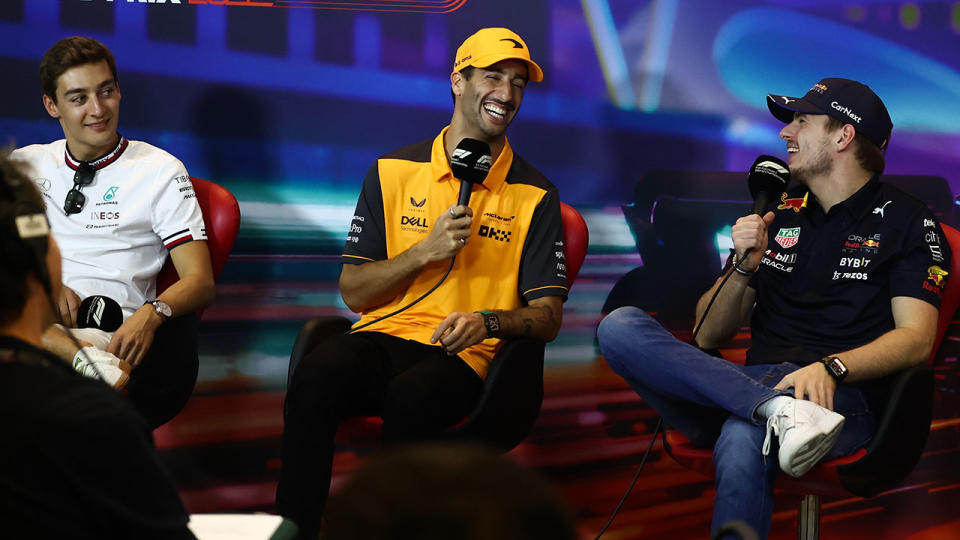 Daniel Ricciardo laughs with George Russell and Max Verstappen at an F1 press conference.