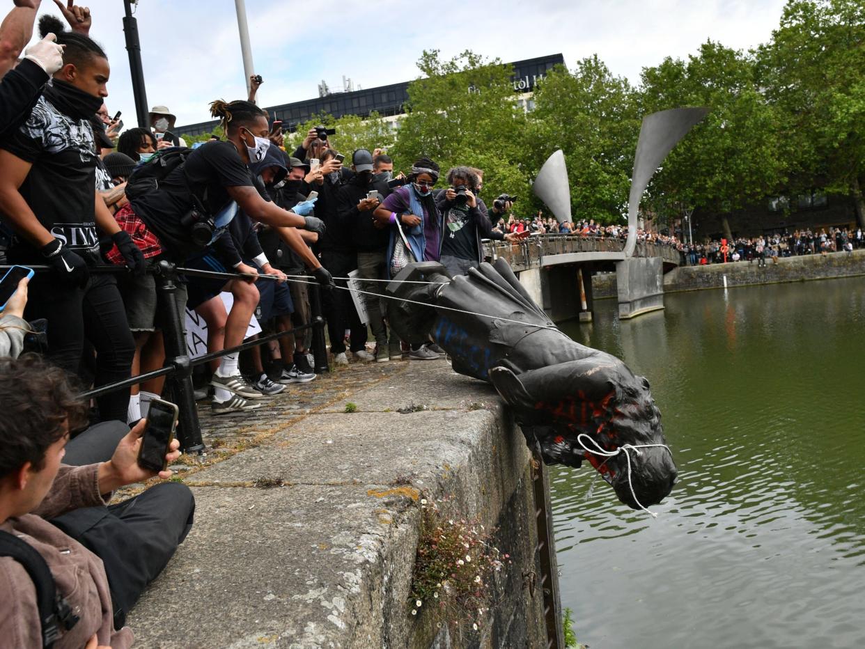 <p>Protesters throw a statue of Edward Colston into Bristol harbour during a Black Lives Matter rally in June last year</p> (PA)