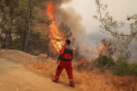 Firefighters work in the smoke-engulfed Mazi area as wildfires rolled down the hill toward the seashore, forcing people to be evacuated, in Bodrum, Mugla, Turkey, Sunday, Aug. 1, 2021. More than 100 wildfires have been brought under control in Turkey, according to officials. The forestry minister tweeted that five fires are continuing in the tourist destinations of Antalya and Mugla. (AP Photo/Emre Tazegul)