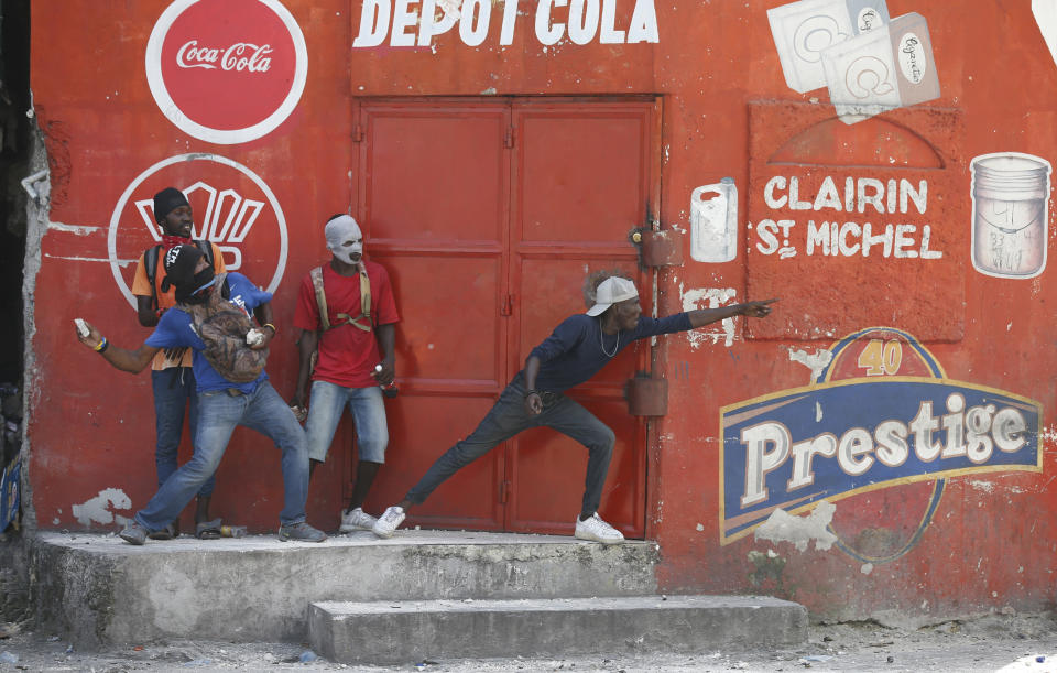 Demonstrators clash with people from the neighborhood during anti-government protests in Port-au-Prince, Haiti, Friday, Oct. 11, 2019. Protesters burned tires and spilled oil on streets in parts of Haiti's capital as they renewed their call for the resignation of President Jovenel Moïse just hours after a journalist was shot to death. (AP Photo/Rebecca Blackwell)