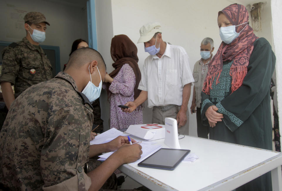 A soldier registrates the local population before they get vaccinated in Kesra,130 kilometers (80 miles) south of Tunis, Tuesday, July 13, 2021. As part of the efforts from the Tunisian government to try to stop the increasing number of infections in the country, the militaries were deployed to some cities and rural areas hardly affected by COVID-19 or with a very low rate of vaccination, to vaccinate people. (AP Photo/Saber Zidi)