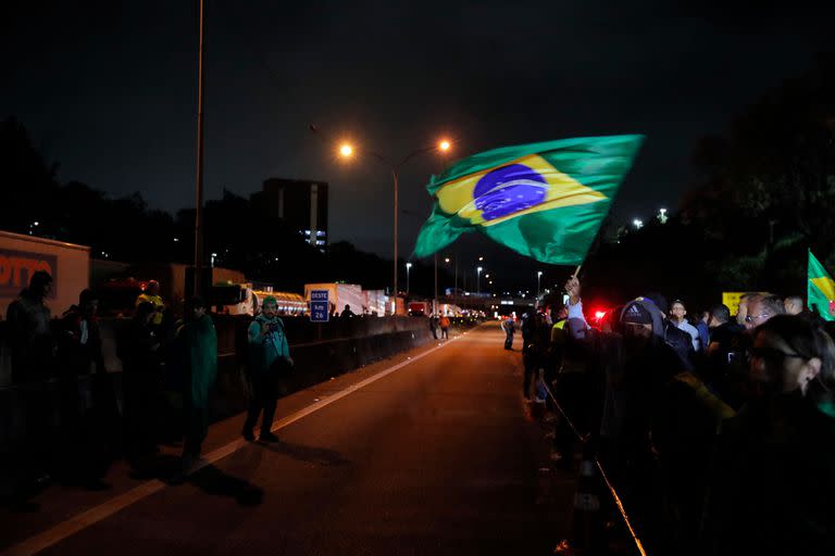 Supporters of President Jair Bolsonaro demonstrate during a blockade on Castelo Branco highway, on the outskirts of Sao Paulo, Brazil, on November 1, 2022. - Supporters of Brazilian President Jair Bolsonaro blocked major highways for a second day as tensions mounted over his silence after narrowly losing re-election to bitter rival Luiz Inacio Lula da Silva. Federal Highway Police (PRF) on Tuesday reported more than 250 total or partial road blockages in at least 23 states by Bolsonaro supporters, while local media said protests outside the country's main international airport in Sao Paulo delayed passengers and led to several flights being cancelled. (Photo by CAIO GUATELLI / AFP)