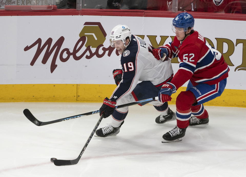 Montreal Canadiens defenseman Justin Barron (52) tries to slow Columbus Blue Jackets center Liam Foudy (19) during the first period of an NHL hockey game Saturday, March 25, 2023, in Montreal. (Peter McCabe/The Canadian Press via AP)