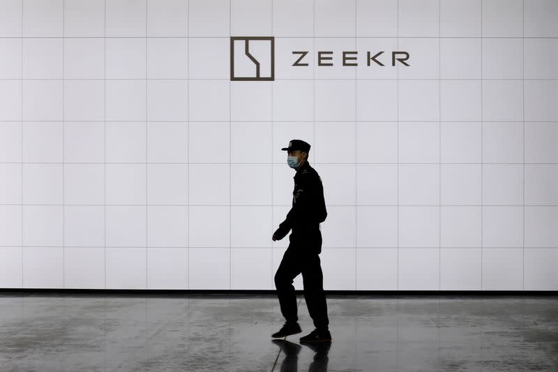 FILE PHOTO: Security guard walks past a sign of Geely's new brand Zeekr at its factory in Ningbo