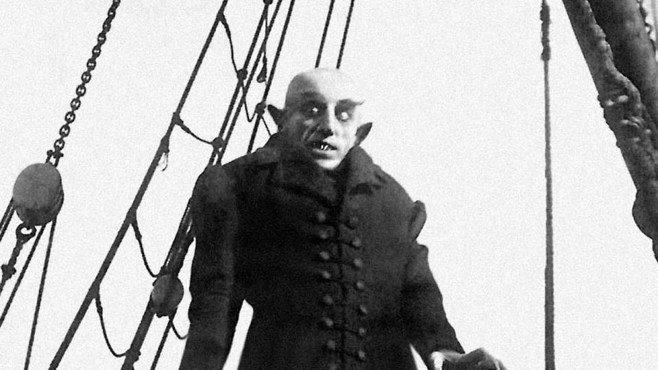 a scene from the classic horror movie nosferatu featuring the titular creature leering in black and white