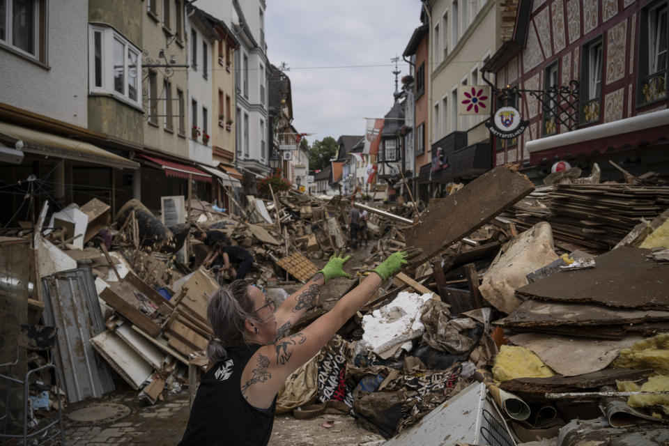 A woman throws away rubbish in the centre of Bad Neuenahr-Ahrweiler, Germany, Monday July 19, 2021. More than 180 people died when heavy rainfall turned tiny streams into raging torrents across parts of western Germany and Belgium, and officials put the death toll in Ahrweiler county alone at 110. (AP Photo/Bram Janssen)