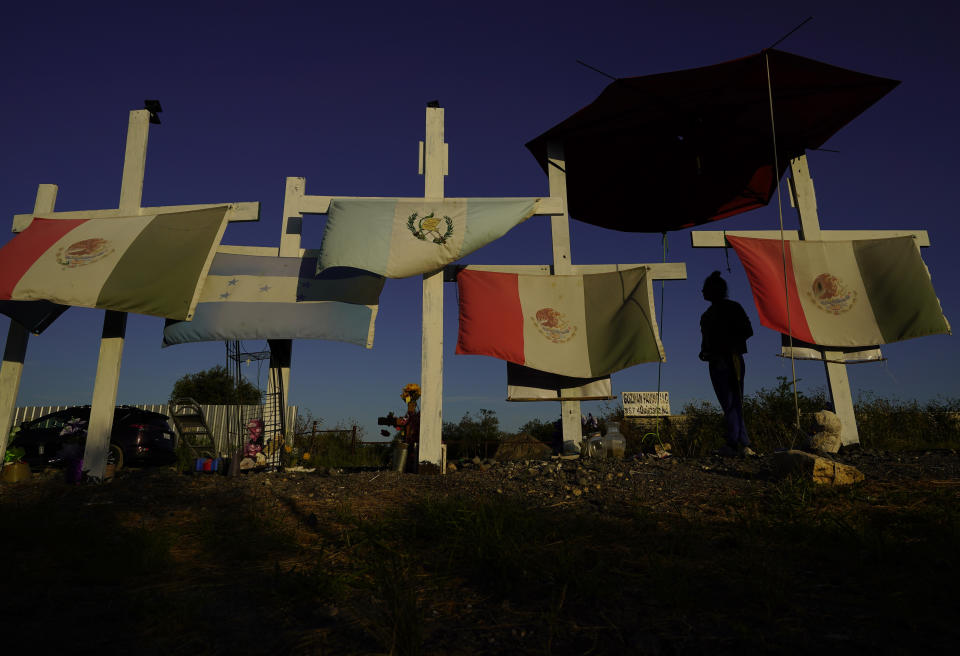 A man walks along some of the 53 crosses that are part of a makeshift memorial at the site where officials found dozens of people dead in an abandoned semitrailer containing suspected migrants last summer, Tuesday, June 27, 2023, in San Antonio. U.S. authorities announced the arrests of four more people in connection to the smuggling deaths of 53 migrants, including eight children, who were left in a tractor trailer in the scorching Texas summer. (AP Photo/Eric Gay)