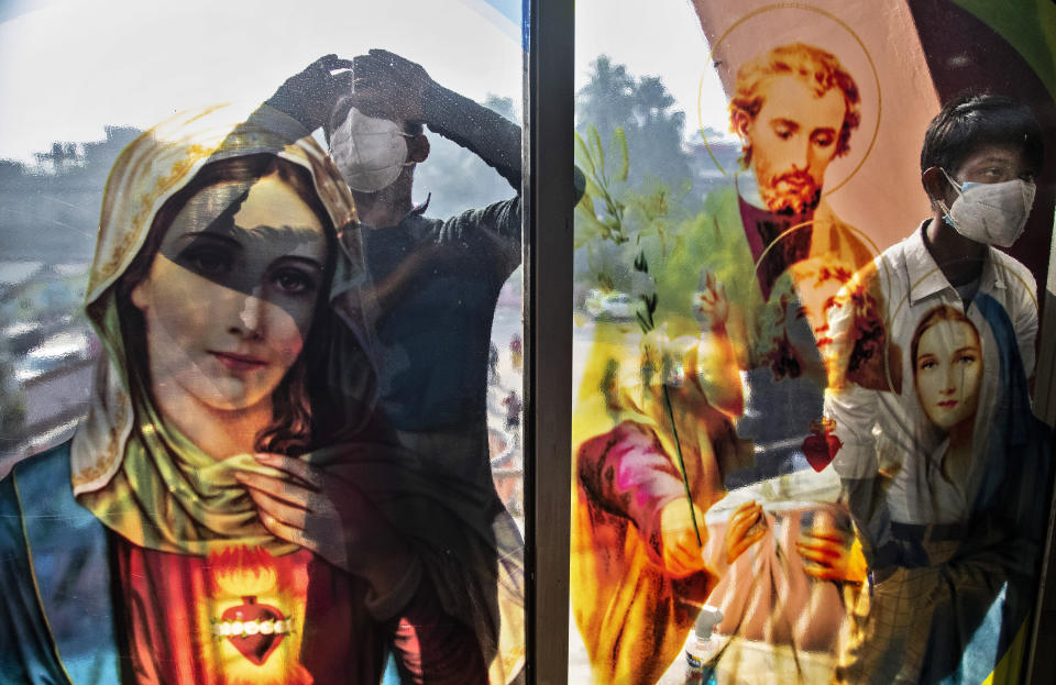 Indian Christian boys wearing face masks as a precaution against the coronavirus peep through the glass of the church as they are not allowed to attend the Christmas mass due to COVID-19 restrictions in Gauhati, India, Friday, Dec. 25, 2020. (AP Photo/Anupam Nath)