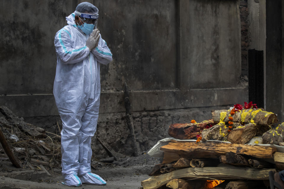 A relative in protective suit performs last rituals as the body of a person who died of COVID-19 is cremated in Gauhati, India, Monday, May 24, 2021. India crossed another grim milestone Monday of more than 300,000 people lost to the coronavirus as a devastating surge of infections appeared to be easing in big cities but was swamping the poorer countryside. (AP Photo/Anupam Nath)