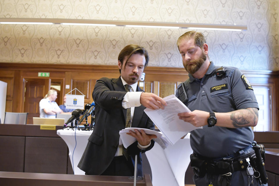 A man hands out copies of the court verdict on American rapper A$AP Rocky at Stockholm District Court, in Stockholm, Sweden, Wednesday Aug. 14, 2019. Swedish court on Wednesday found American rapper A$AP Rocky guilty of assault for his role in a June 30 street brawl in Stockholm. (Anders Wiklund / TT via AP)