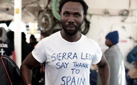 A migrant shows a thank you note to Spain written on his t-shirt as he waits to disembark from the Aquarius rescue ship in the port of Valencia - Credit: Handout/Reuters