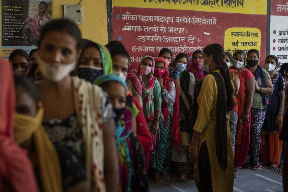 People wait in line for the arrival of vaccines during a vaccination drive against the coronavirus at a government health centre in Noida, a suburb of New Delhi, India, Tuesday, Aug. 3, 2021. (AP Photo/Altaf Qadri)