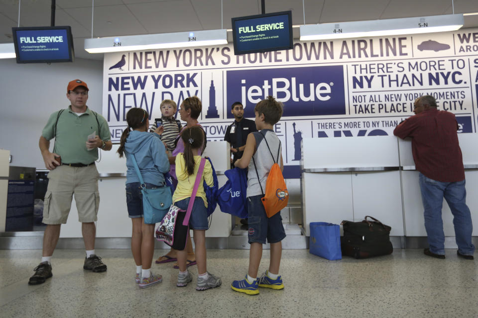 Tom Price, left, and his wife Zsuzsa, center, prepare to check in with their children, from left, Hailye, 10, Callum, 4, Keira, 6, and Owen, 9, at the JetBlue counter, Saturday, Sept. 21, 2013 at JFK airport in New York. Dozens of families with children with autism have practiced air travel at New York's Kennedy International Airport. JetBlue Airways and the nonprofit Autism Speaks held the practice run for families at JFK on Saturday. (AP Photo/Mary Altaffer)