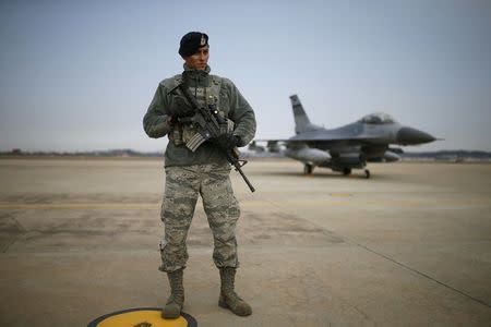 A U.S. soldier stands guard in front of their Air F-16 fighter jet at Osan Air Base in Pyeongtaek, South Korea, January 10, 2016. REUTERS/Kim Hong-Ji