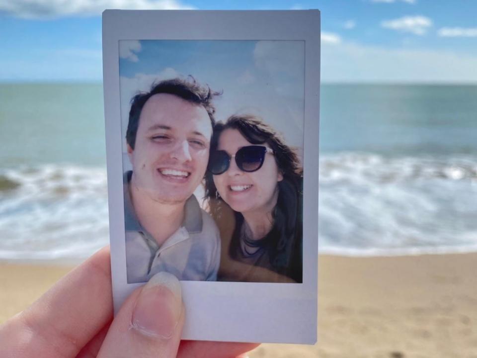 hand holding a polaroid photo of alexis and her partner on a beach