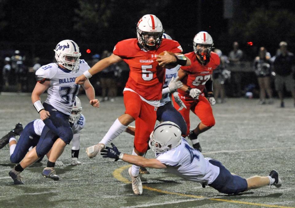 Hingham quarterback John Nicholas steps over an attempted tackle by Rockland defender Jacob Coulstring, right, on a keeper during the high school football season season opener at Hingham High School, Friday, Sept. 9, 2022.