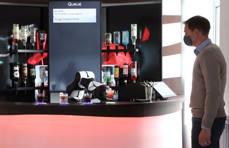 An employee looks on as a robotic arm serves a Campari Soda long drink in Zurich