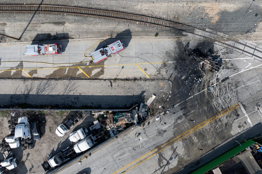 The tractor portion of a big rig, right, is shown in an aerial view on Thursday, Feb. 15, 2024, in the Wilmington section of Los Angeles. Several Los Angeles firefighters were injured, two critically, when an explosion occurred as they responded to a truck with pressurized cylinders that were on fire early Thursday, authorities said. (AP Photo/William Liang)