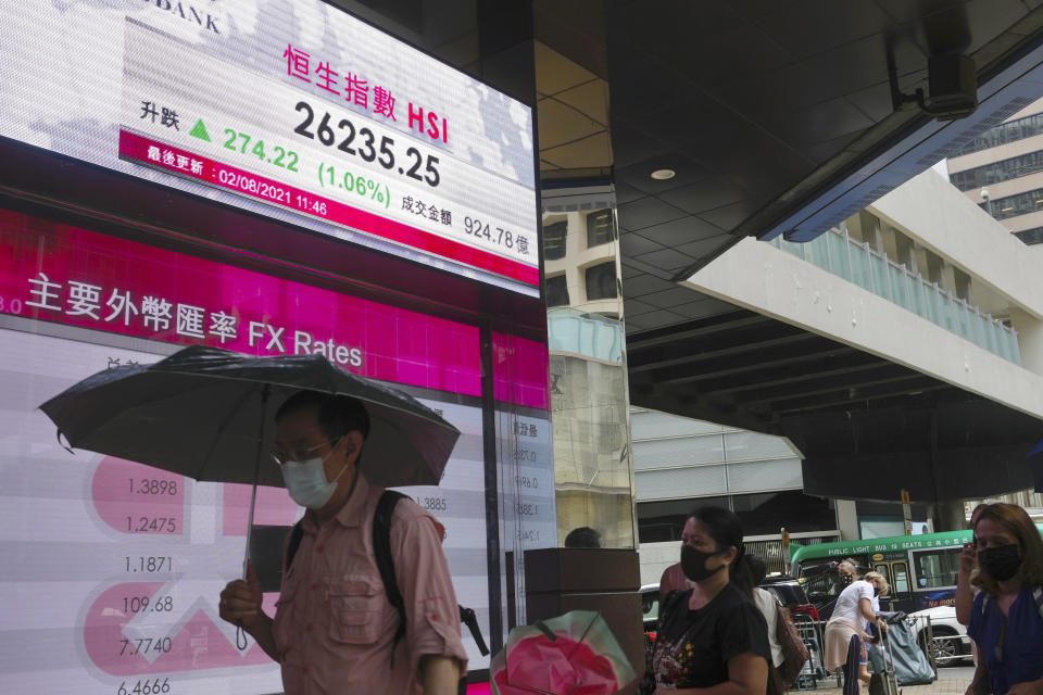 A man walks past a bank's electronic board showing the Hong Kong share index at Hong Kong Stock Exchange in Hong Kong Monday, Aug. 2, 2021. Asian stocks have started the week higher, even as China reported a slowdown in manufacturing activity and countries in the region continue to be hammered by the delta variant. (AP Photo/Vincent Yu)