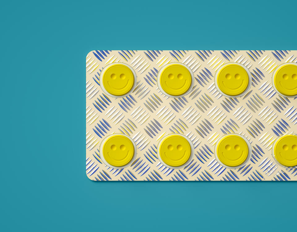 Yellow happy face pills on a patterned background, conveying wellness and positivity