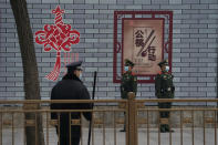 Security personnel stand guard at a retail district near the Great Hall of the People where the opening session of the Chinese People's Political Consultative Conference (CPPCC) is held in Beijing on Thursday, March 4, 2021. The sign means “to encourage the use of serving chopsticks for shared dishes.” (AP Photo/Ng Han Guan)