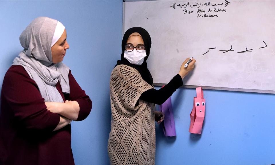 Rawan Haj-Hussein, right, looks back at Hiba Kattin as she writes Arabic letters on the board as Kattin teaches a class on Arabic at the Murfreesboro Muslim Youth Center on Monday, April 11, 2022.