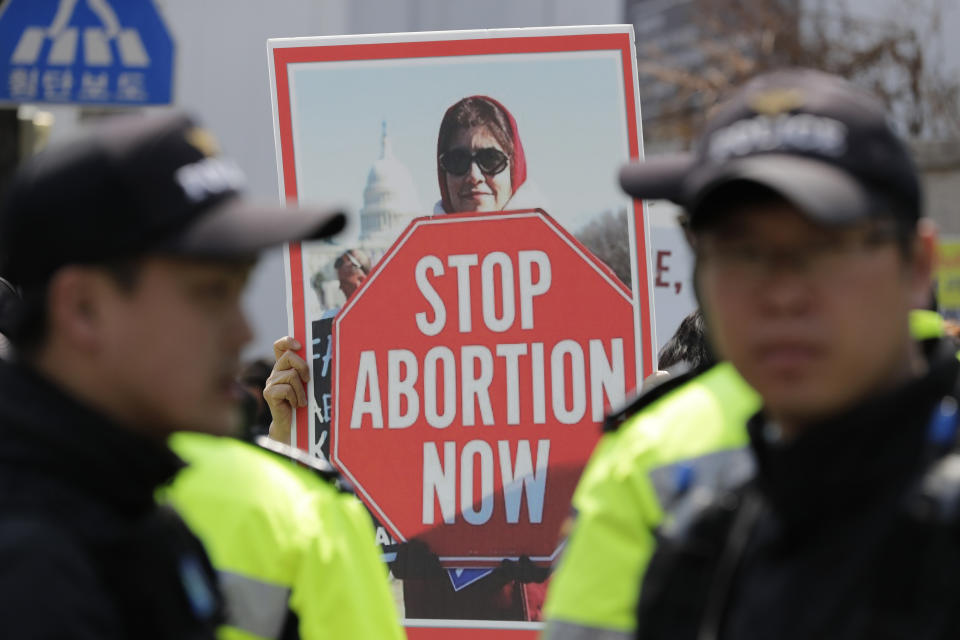 A pro-life demonstrator holds a banner near police officers during a rally supporting South Korea's anti-abortion regulations outside of the Constitutional Court in Seoul, South Korea, Thursday, April 11, 2019. In a major reversal, South Korea's Constitutional Court on Thursday ordered the easing of the country's decades-long ban on abortions, one of the strictest in the developed world. (AP Photo/Lee Jin-man)