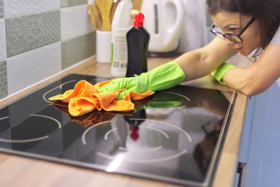 Woman doing final cleaning on induction cooktop.