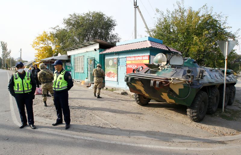 Traffic police officers and members of Kyrgyz armed forces stand guard in the street in Bishkek