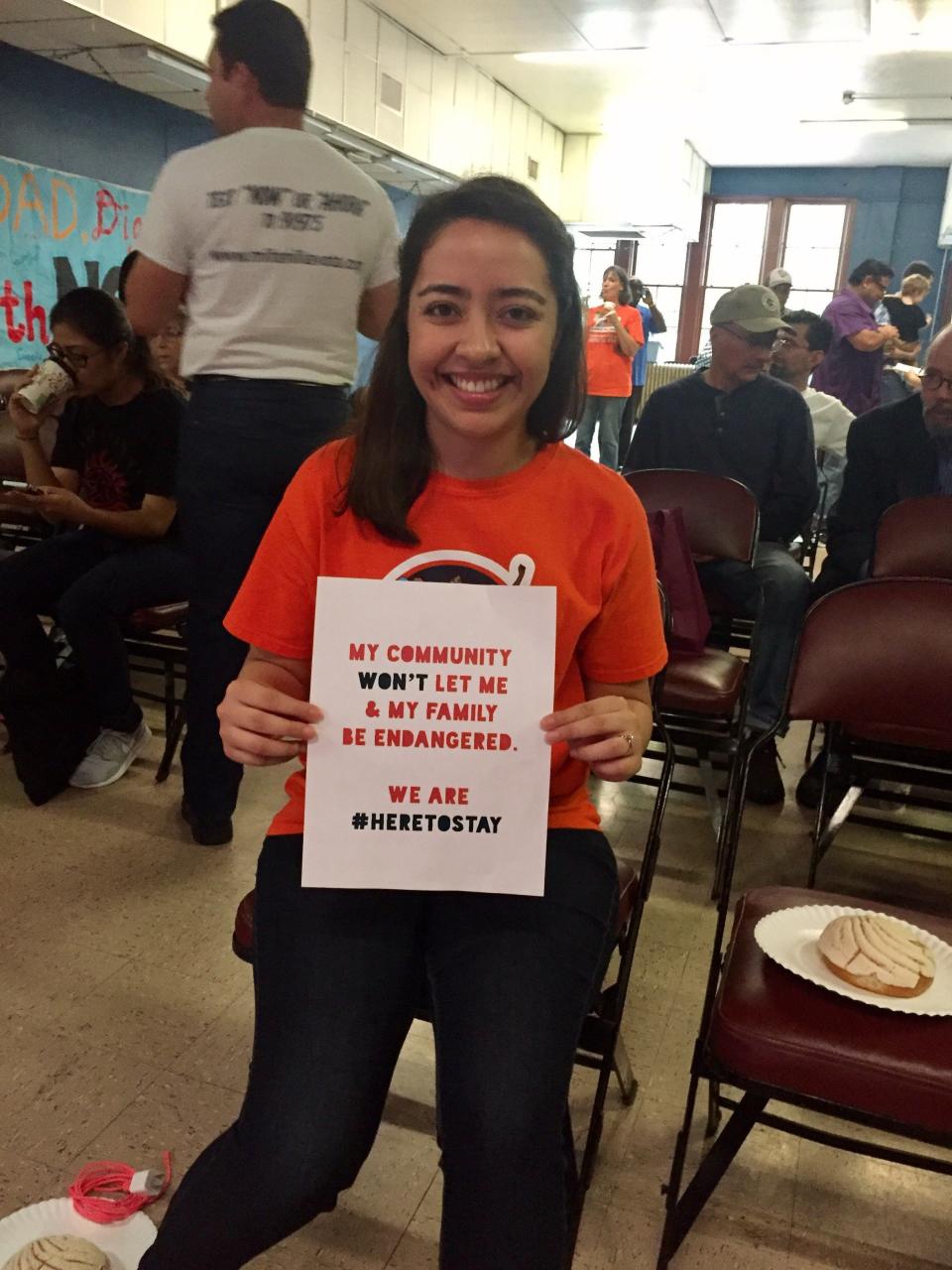 Karla Perez poses with a #HereToStay sign. 