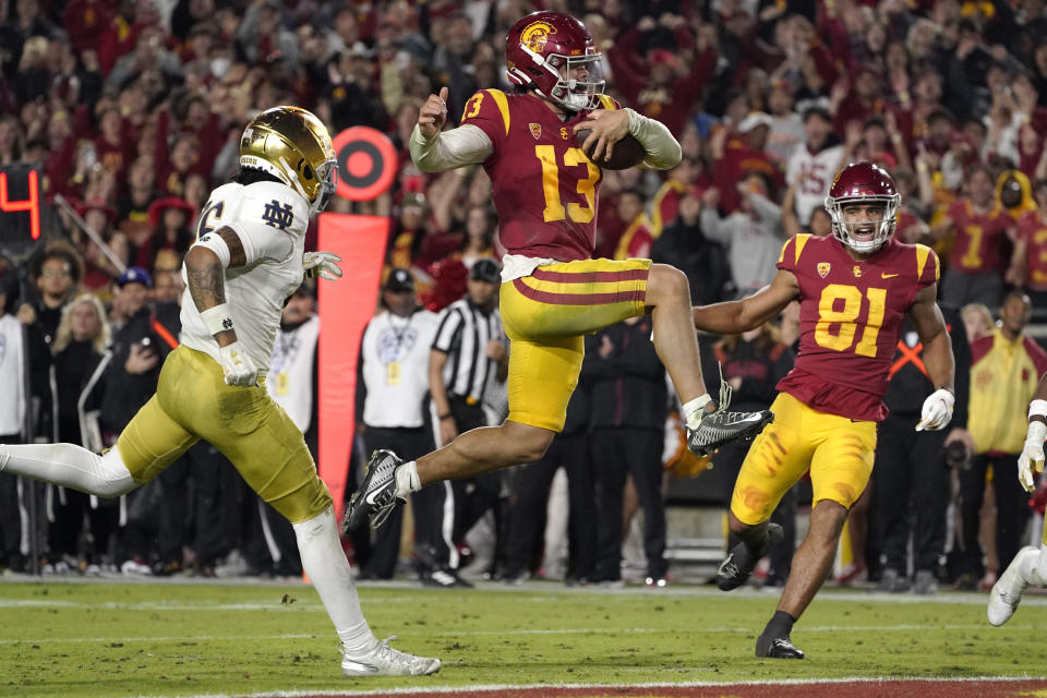 FILE - Southern California quarterback Caleb Williams jumps in for a touchdown as Notre Dame safety Xavier Watts, left, defends and Southern California wide receiver Kyle Ford watches during the second half of an NCAA college football game Saturday, Nov. 26, 2022, in Los Angeles. Southern California quarterback Caleb Williams was named the AP Player of the Year in college football, Thursday, Dec. 8, 2022. (AP Photo/Mark J. Terrill, File)