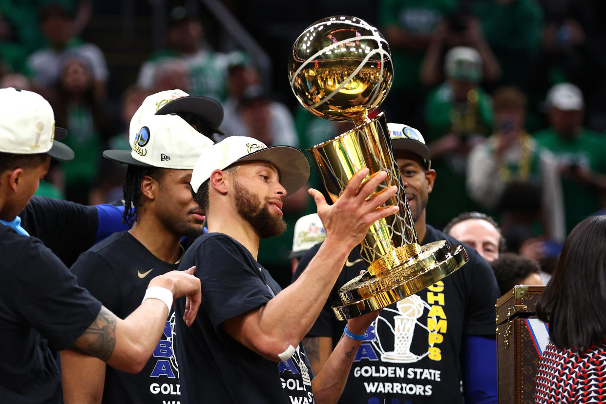 Stephen Curry of the Golden State Warriors raises the Larry O'Brien Championship Trophy after defeating the Boston Celtics in the NBA Finals. (Photo by Elsa/Getty Images)